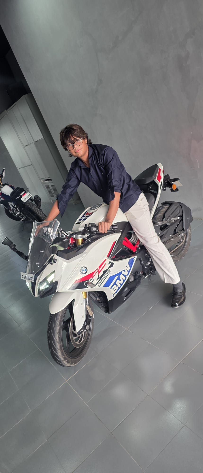Dhruv Shukla posing on a white BMW motorcycle in the showroom